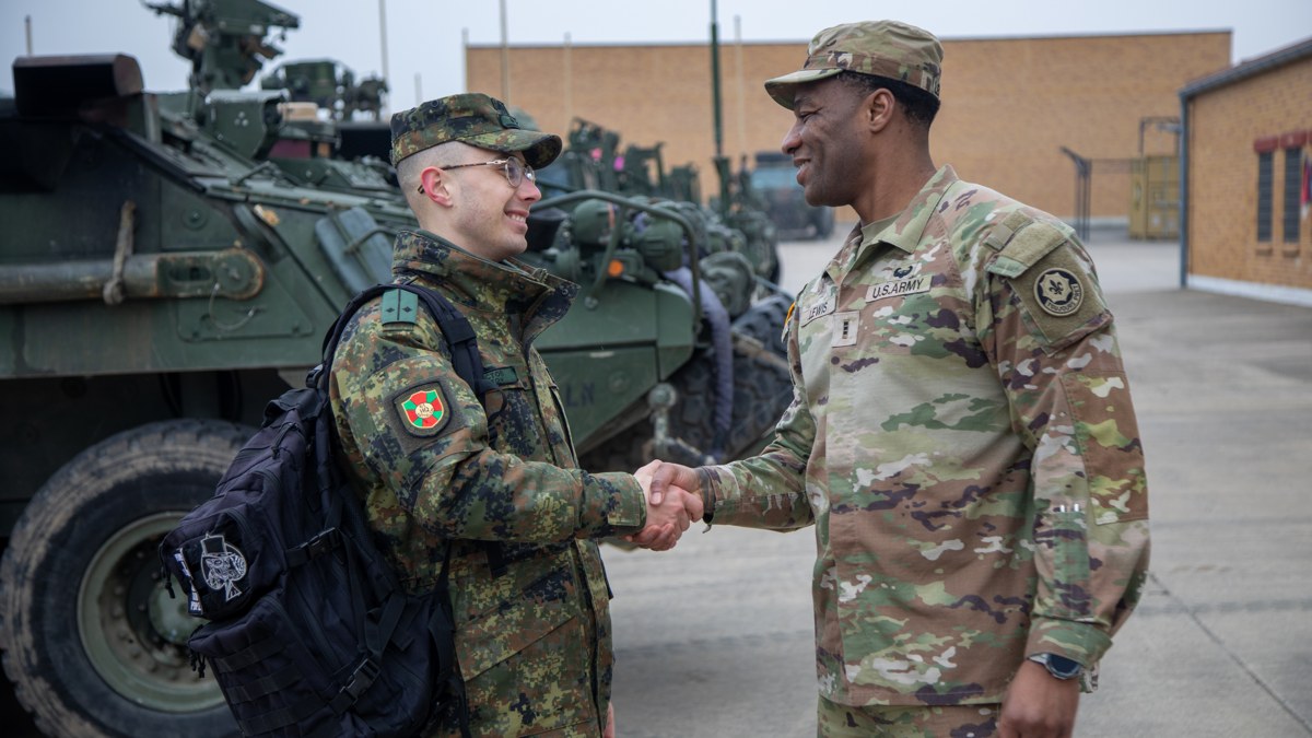 Bulgarian soldier and U.S. Army officer shake hands in front of Stryker vehicles