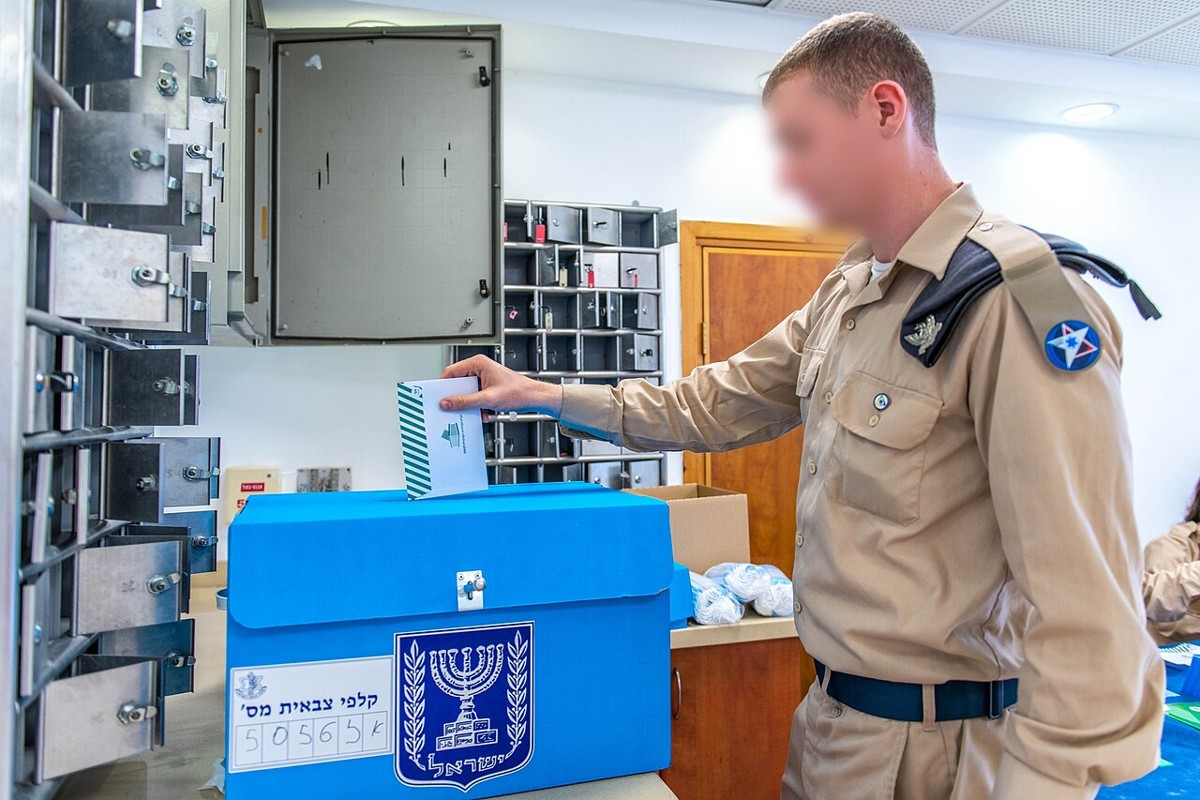 Israeli soldier dropping a ballot envelope into a military polling station box