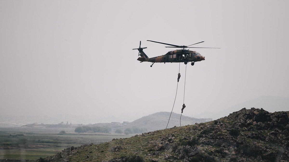 Turkish soldiers fast-roping from a helicopter during a military exercise